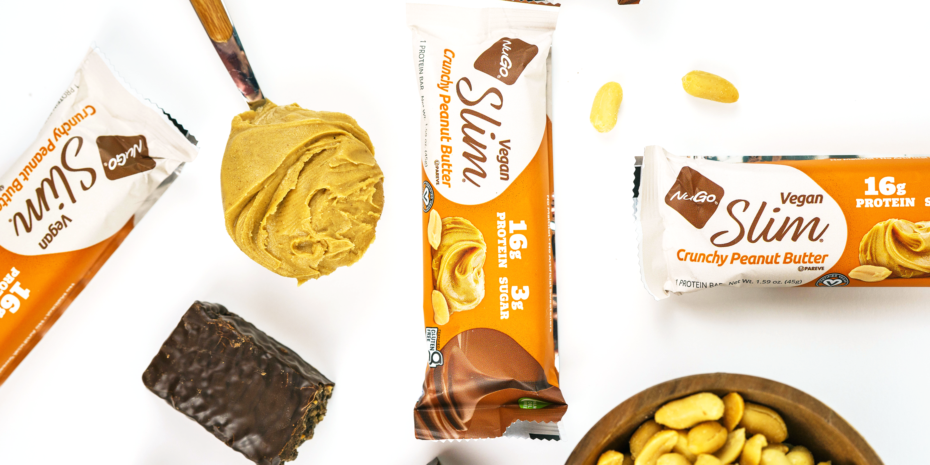 NuGo Slim Crunchy Peanut Butter wrapped bars with a bowl of peanuts and spoon of peanut butter