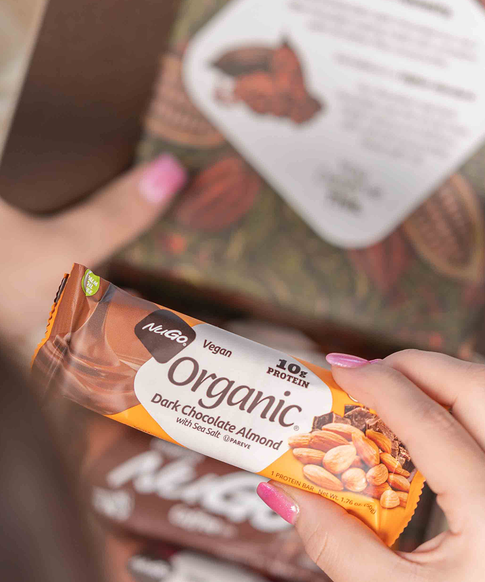 Up close NuGo Organic Dark Chocolate Almond Bar in Woman's Hand