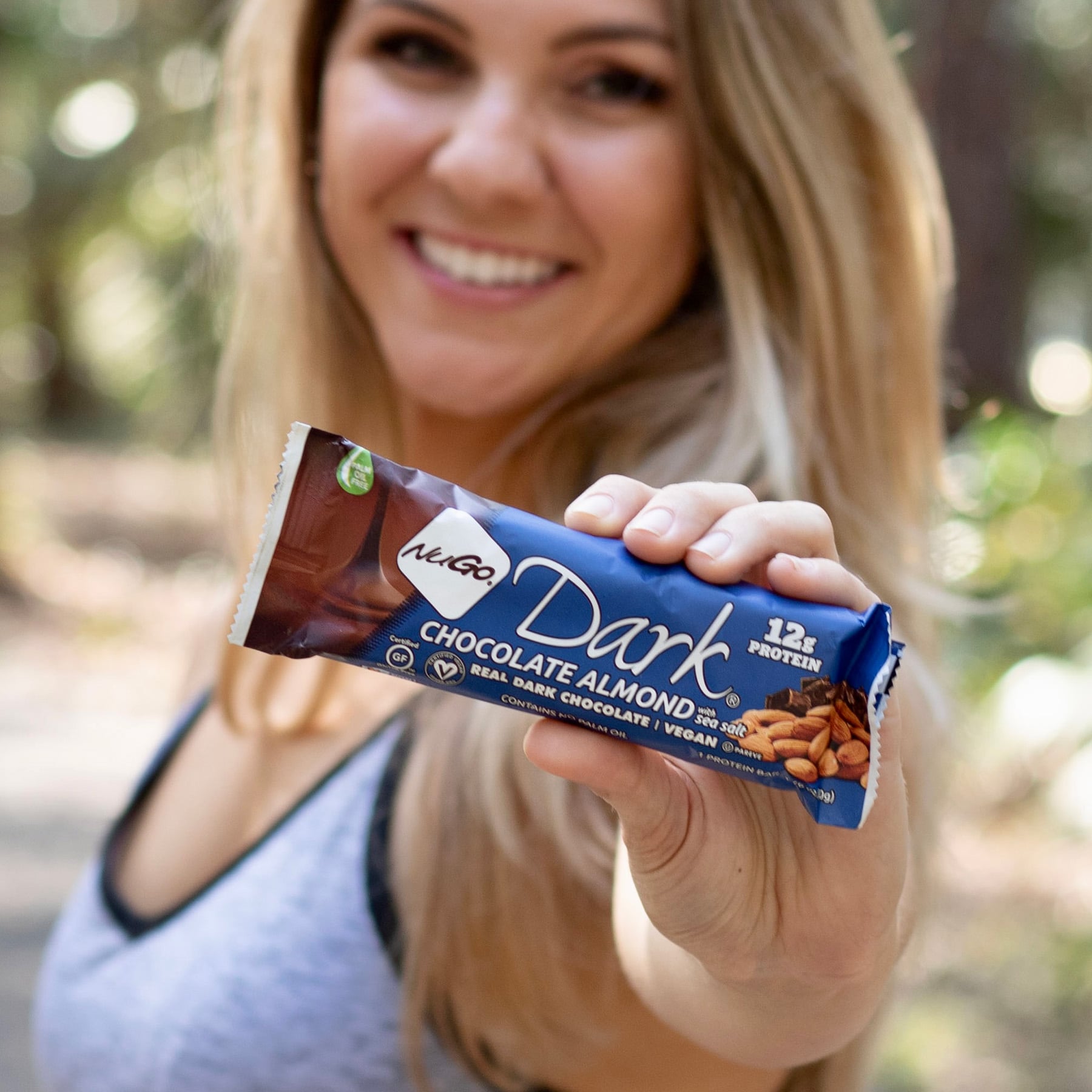 Woman Smilling and holding a Chocolate Almond Bar close up