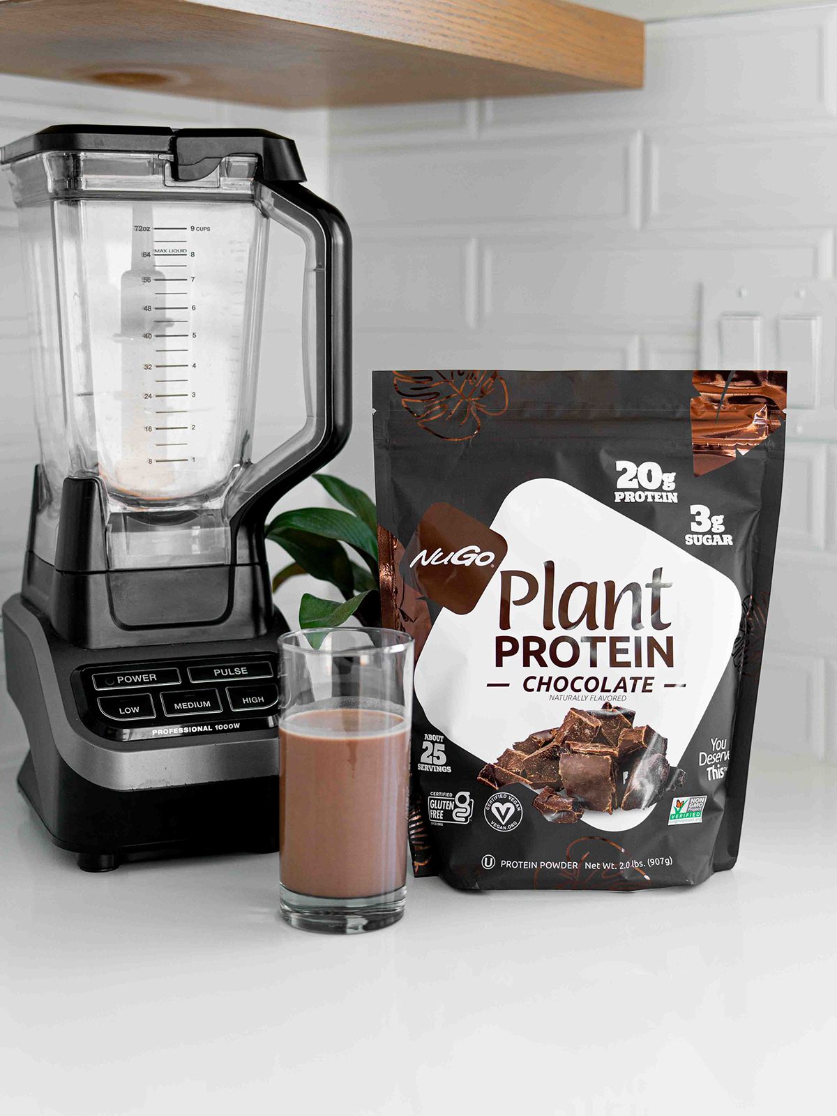 Chocolate Protein powder bag next to blender and glass of protein drink