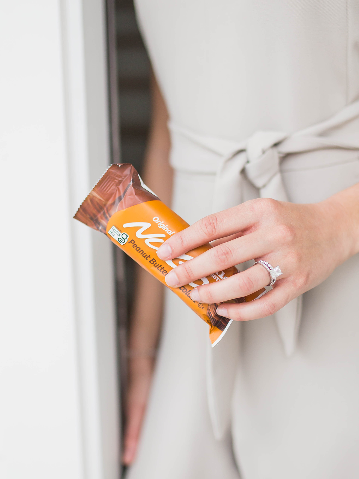 Close up Woman holding a NuGo Original Peanut Butter Chocolate in front of body